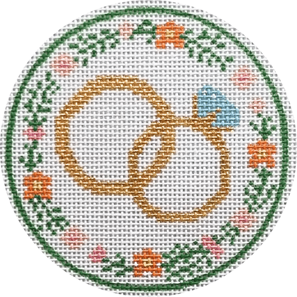 Circular needlepoint design with a central interlocking wedding rings , surrounded by floral patterns on a white background