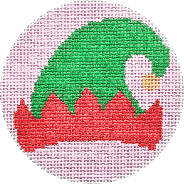 A circular needlepoint canvas featuring a festive elf hat design. The hat has a bright green crown, a red brim, and a small white and yellow beak on the side, set against a light pink Aida cloth background.